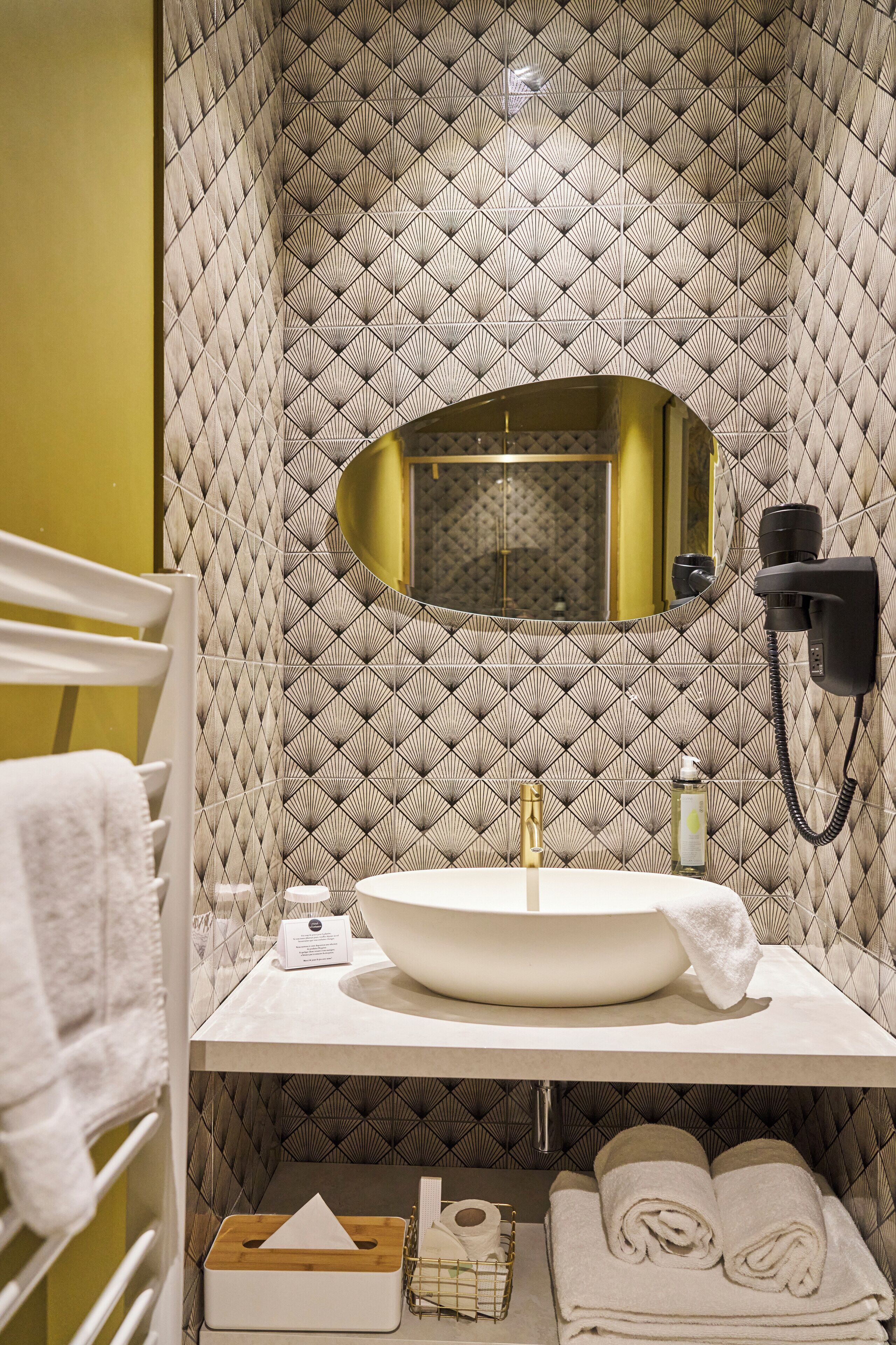 A bathroom with a large sink, a mirror, and a towel rack.