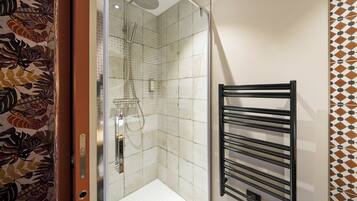 A bathroom with a shower, a towel rack, and patterned walls.