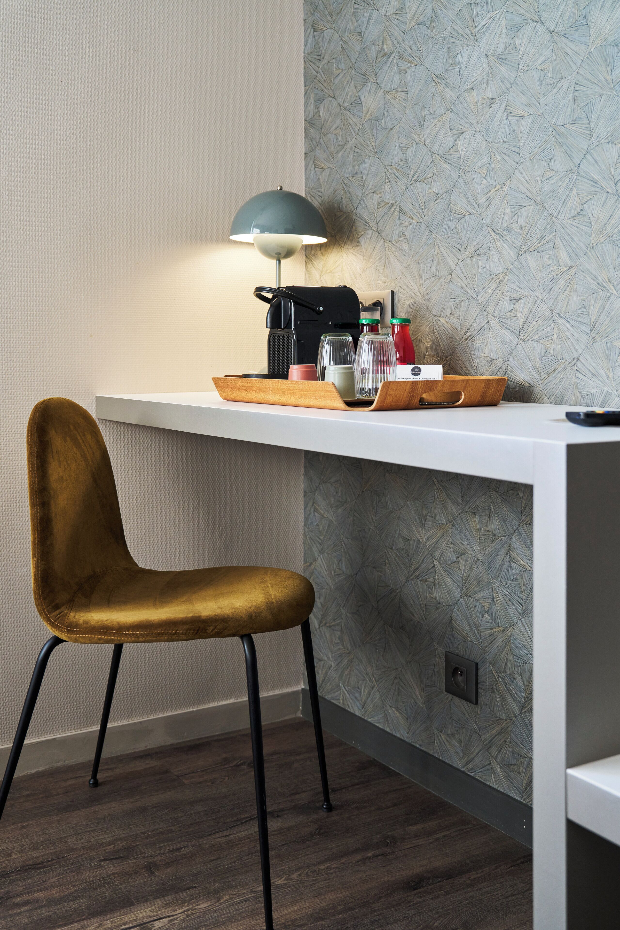 A modern desk with a lamp, a chair, and a tray with various items.