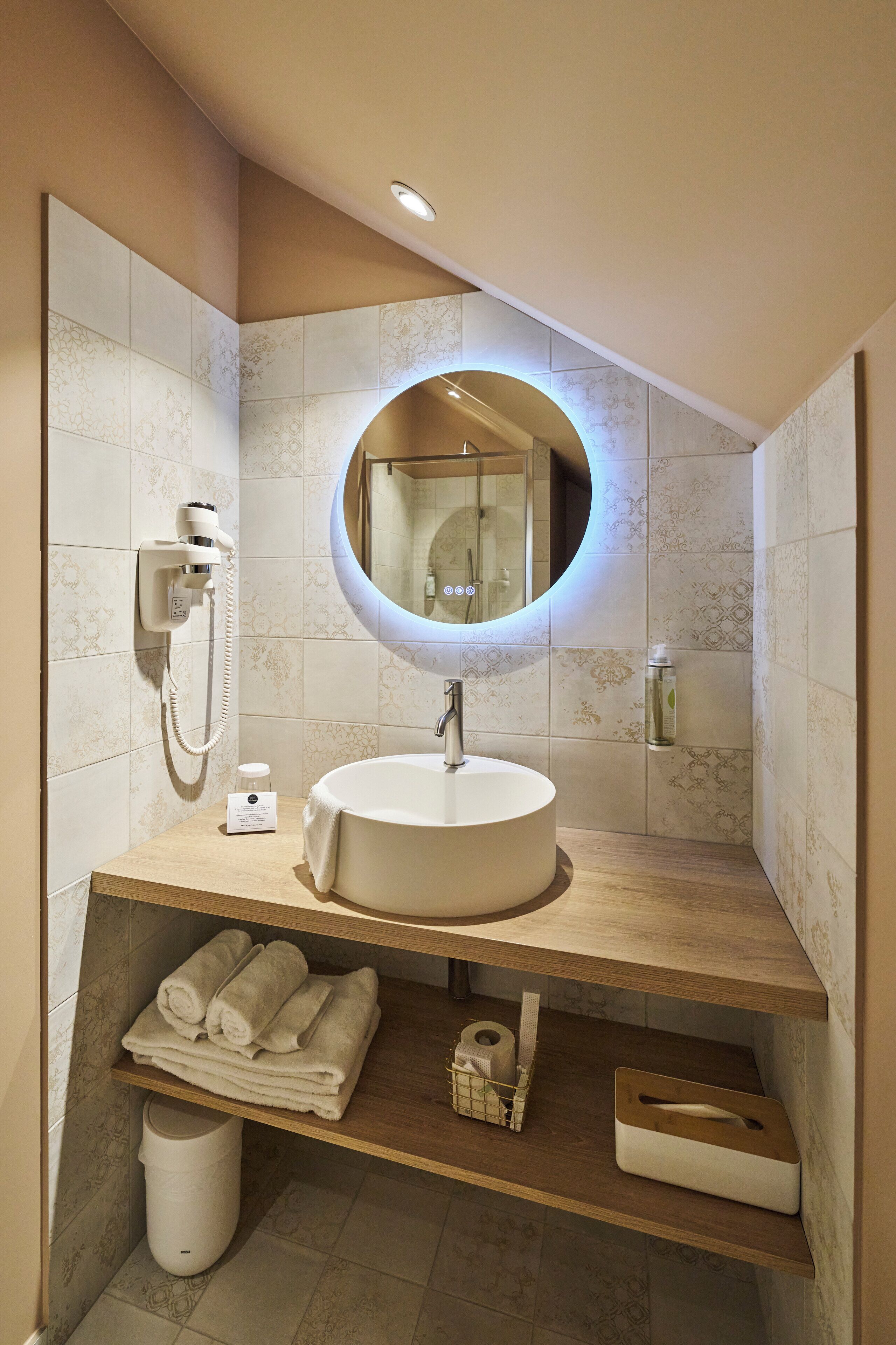 Une salle de bain moderne avec un miroir rond, un lavabo et un porte-serviettes.