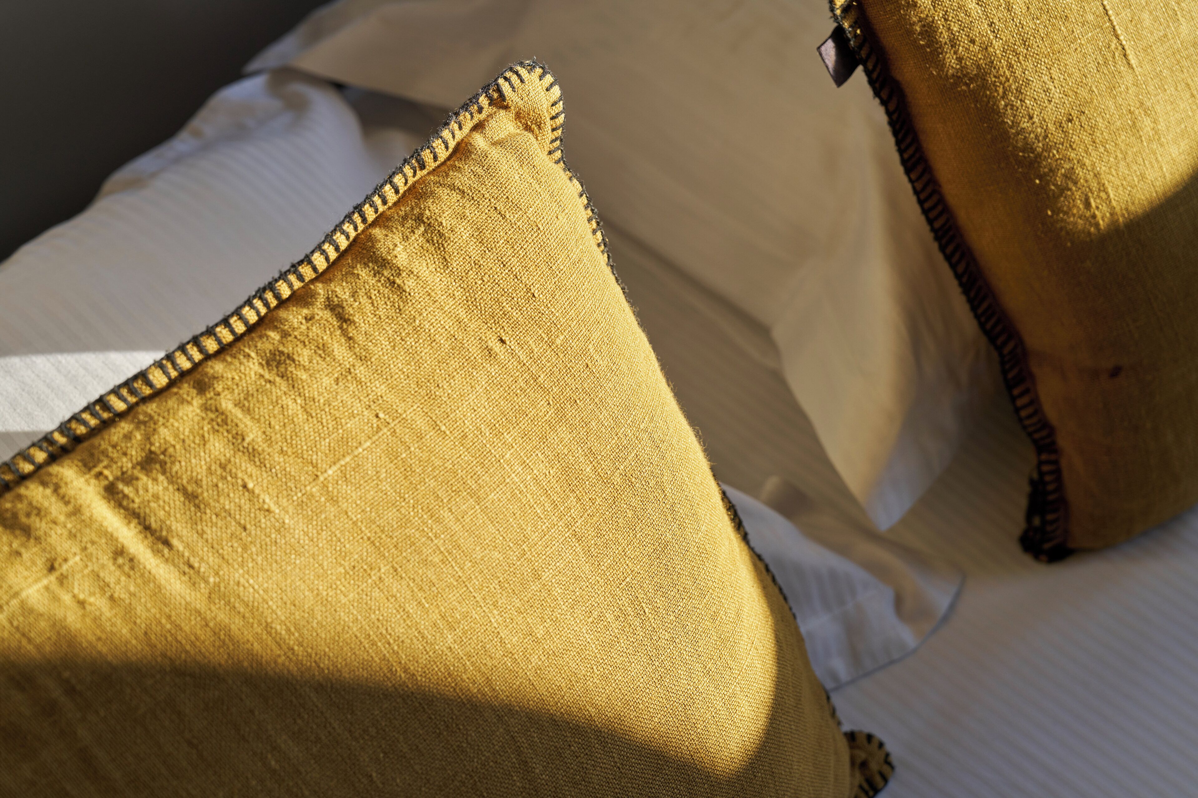 A close-up of a yellow pillow with a textured fabric and a zipper detail.