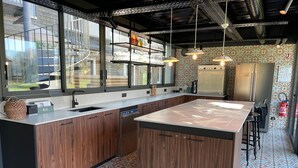 A modern kitchen with wooden cabinets, a large island, and a patterned tile floor. - Hôtel Le Corbusson Laval Ouest (Saint-Berthevin)