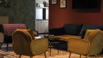 A living room with a sofa, two armchairs, a coffee table, and a television.