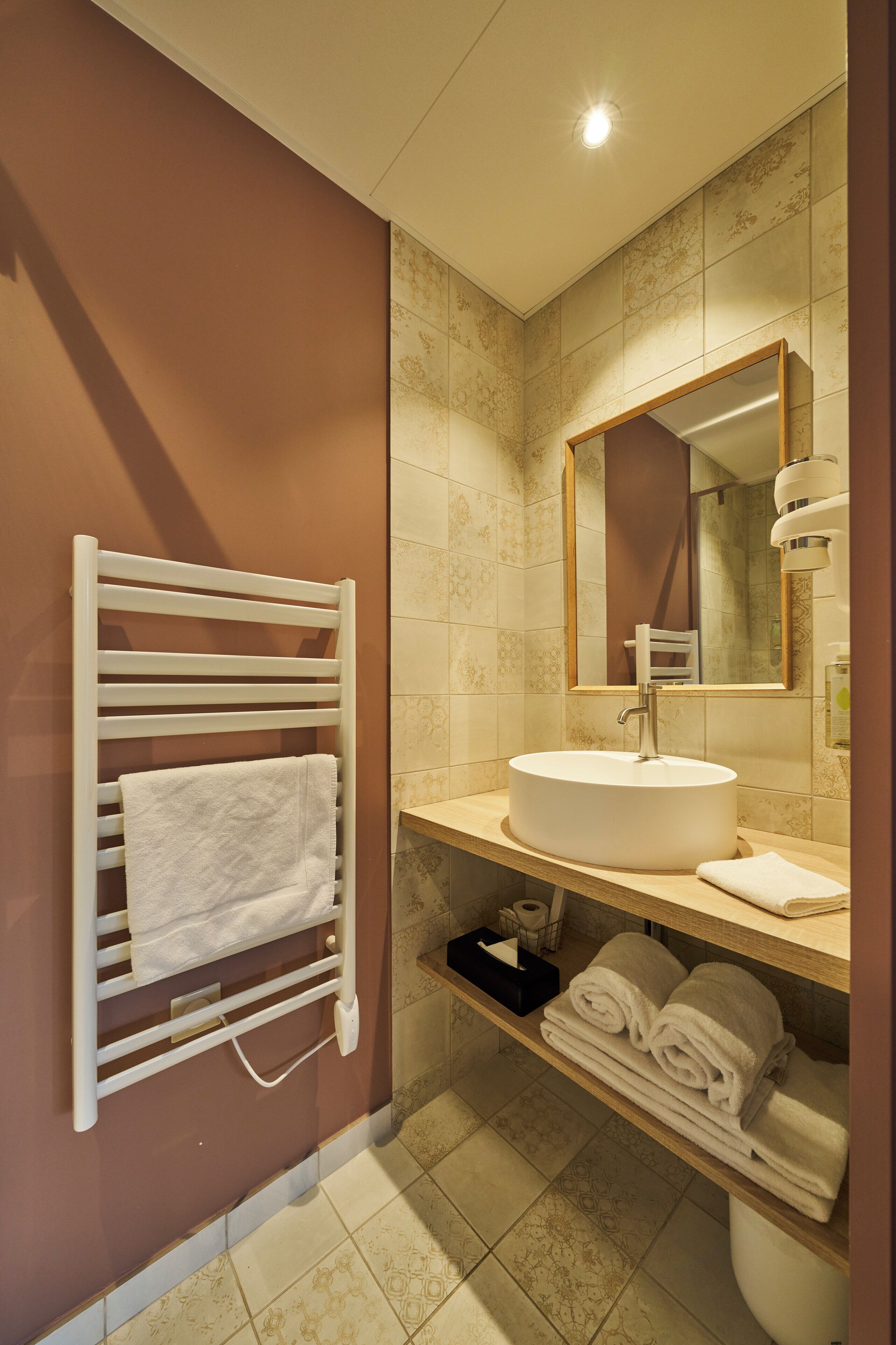 Un baño moderno con un lavabo redondo, un perchero y un espejo.