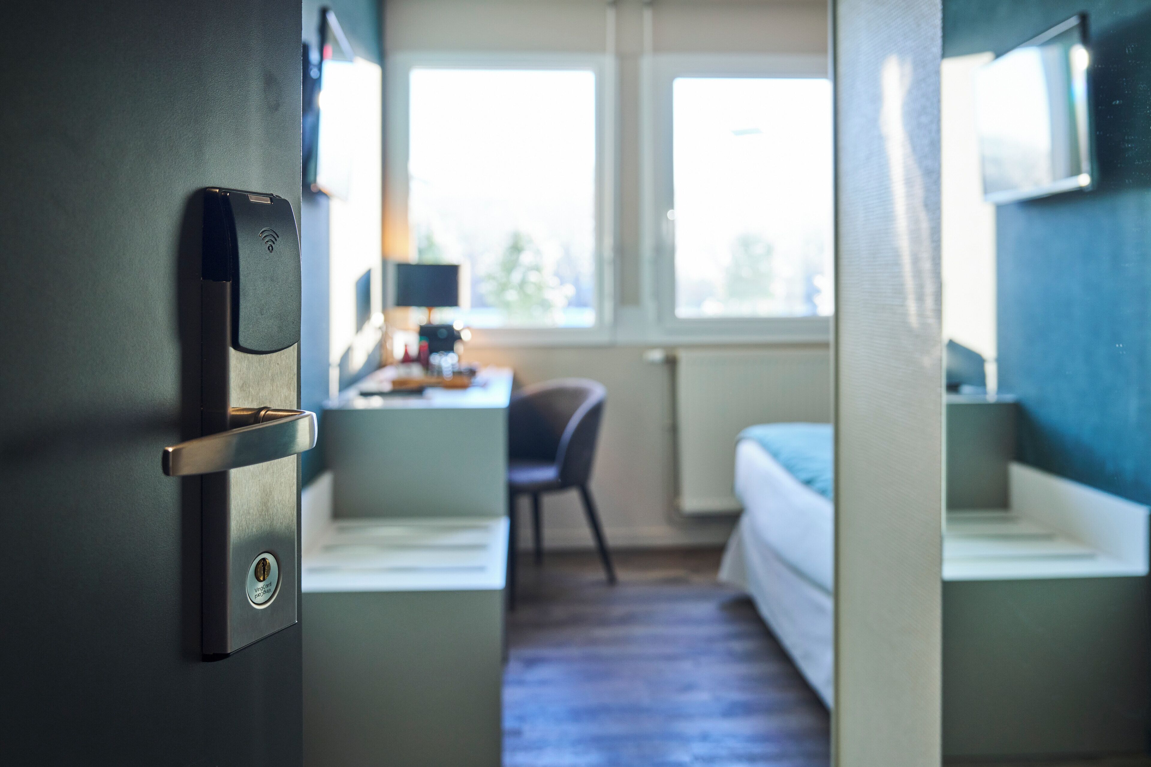 A hotel room with a bed, a desk, and a chair.