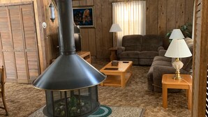 A cozy living room with a wood-paneled interior, a large fireplace, a sofa, and a coffee table.