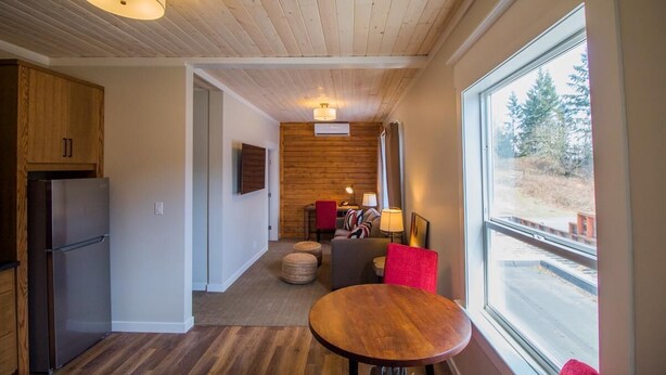 A modern kitchen with a built-in refrigerator, wooden cabinets, and a large window offering a view of the outdoors. - Cranberry Arms Inn (Cassidy)