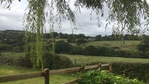 Een houten hek met uitzicht op een landelijk landschap, met velden en verre bomen.
