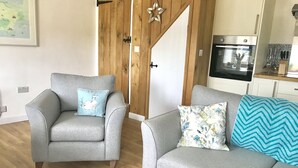 Een moderne woonkamer met een grijze bank, een bijpassende fauteuil en een houten accentmuur.