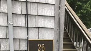 A wooden staircase leading to a house with a sign indicating "26 SPRUCE ROAD UPSTAIRS".