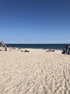 A sandy beach with people sunbathing and walking.