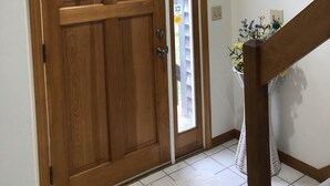 Una puerta de madera con un panel de vidrio, una ventana pequeña y un piso de baldosas blancas.