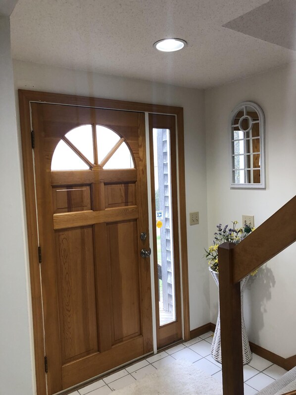 A wooden door with a glass panel, a small window, and a white tiled floor.