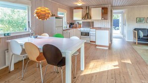 Una cocina moderna con armarios blancos, una mesa de comedor con sillas y una lámpara colgante.