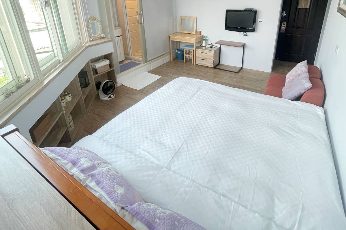Ett sovrum med en säng, ett skrivbord, en tv och ett fönster.