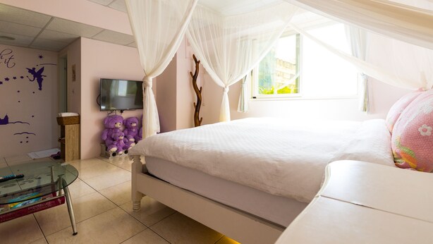 A bedroom with a bed, a TV, a glass table, and a window. - Yi-Jing B&B (Hualien City)