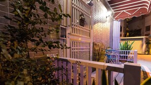 A nighttime view of a building with a brick facade, a metal gate, and a small outdoor seating area with a table and chairs. - Yi-Jing B&B (Hualien City)