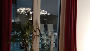 Ett rum med en skjutdörr i glas som leder ut till en balkong, en krukväxt och ett trägolv.