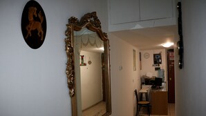 A hallway with a large ornate mirror, a coat rack, and a small desk with a chair. - Roman Place (Rome)