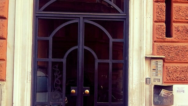 A black metal door with a glass panel and a keypad on the right side. - Roman Place (Rome)