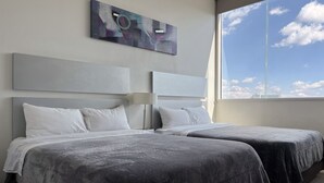A hotel room with two beds, a large window, and a modern abstract painting on the wall. - Lâviu B&B Luxe Suites (San Andrés Cholula)