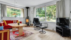 A modern living room with a fireplace, a sofa, a dining table, and a TV. - Awesome home in Knebel with kitchen (Knebel)