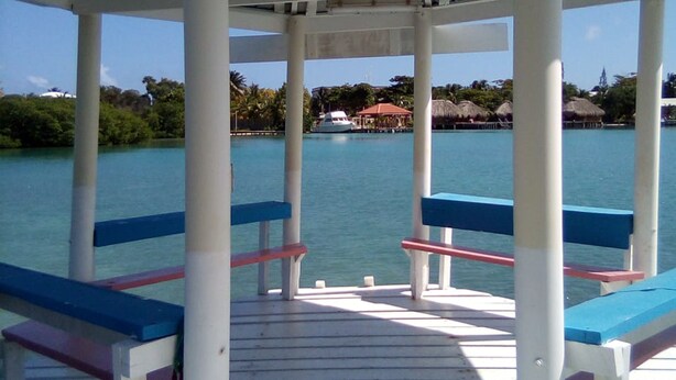 A covered outdoor seating area with benches and a view of the water. - Tropickeas (St. George's Caye)