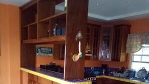 A kitchen with wooden cabinets, a central island, and a tiled backsplash. - Tropickeas (St. George's Caye)