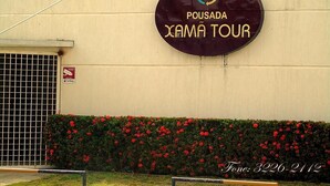 A sign for "Pousada Xama Tour" with a contact number. - Pousada Xamã Tour (João Pessoa)