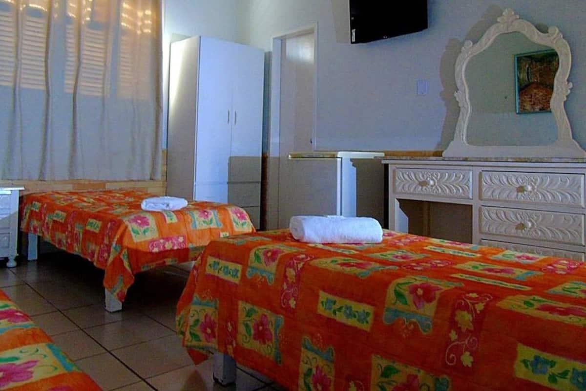 Ein Hotelzimmer mit zwei Betten, einem Schminktisch, einem Fernseher und einem Spiegel.