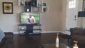 A living room with a television, two sofas, a coffee table, and shelves with various items.