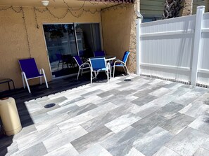 Une terrasse avec un sol carrelé disposé en motif de chevron, du mobilier d’extérieur et une clôture blanche.