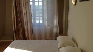 Un dormitorio con cama, una ventana con cortinas, y una lámpara fijada a la pared.