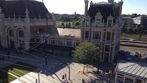 Un edificio histórico con arquitectura ornamentada, una plaza pavimentada y una línea de tranvía.