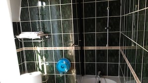 Un baño con bañera, inodoro y grifería de ducha azul.