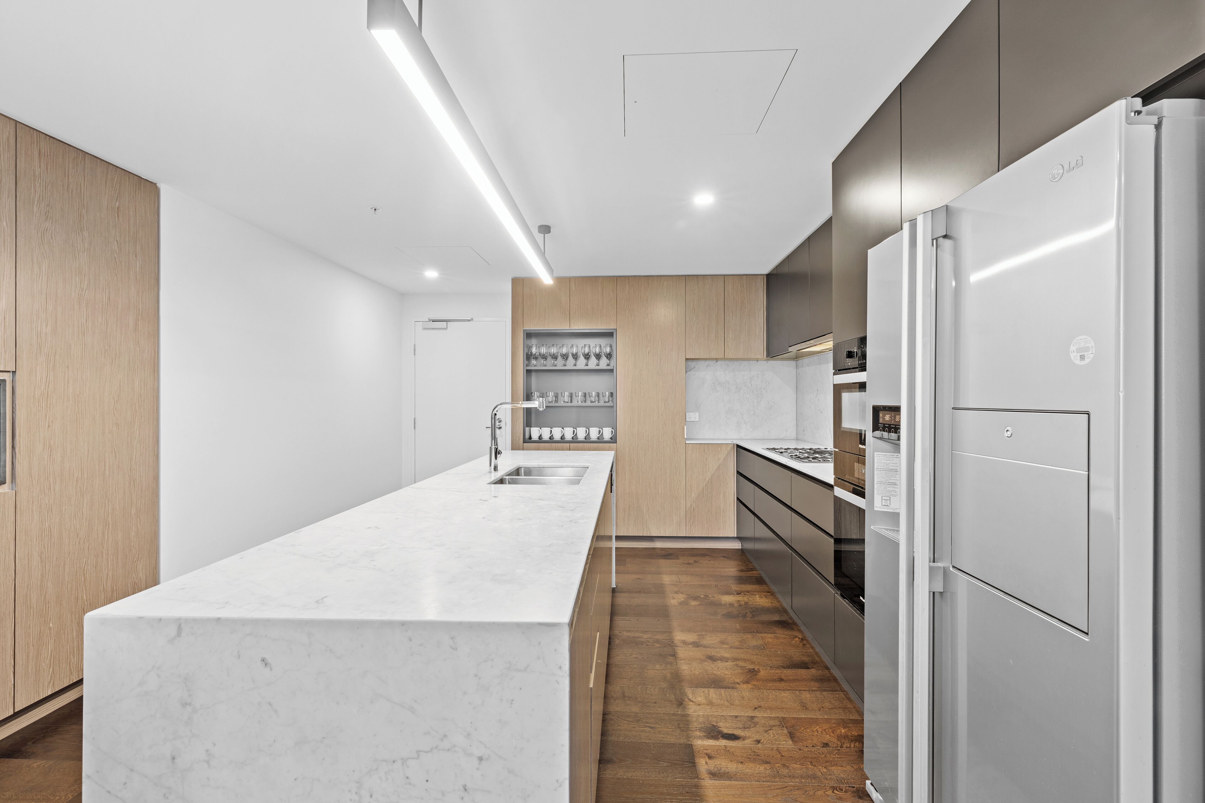 A modern kitchen with a marble countertop, wooden cabinets, and stainless steel appliances.
