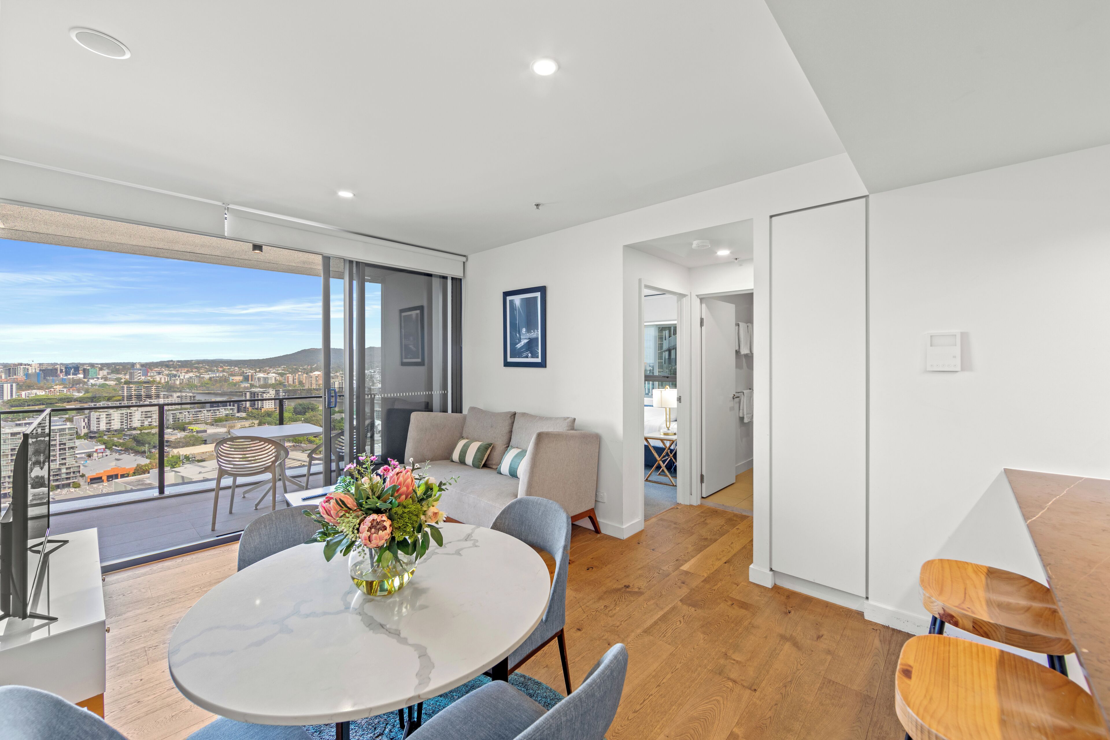 Een moderne woonkamer met een eettafel, bank en een balkon met uitzicht op de stad.