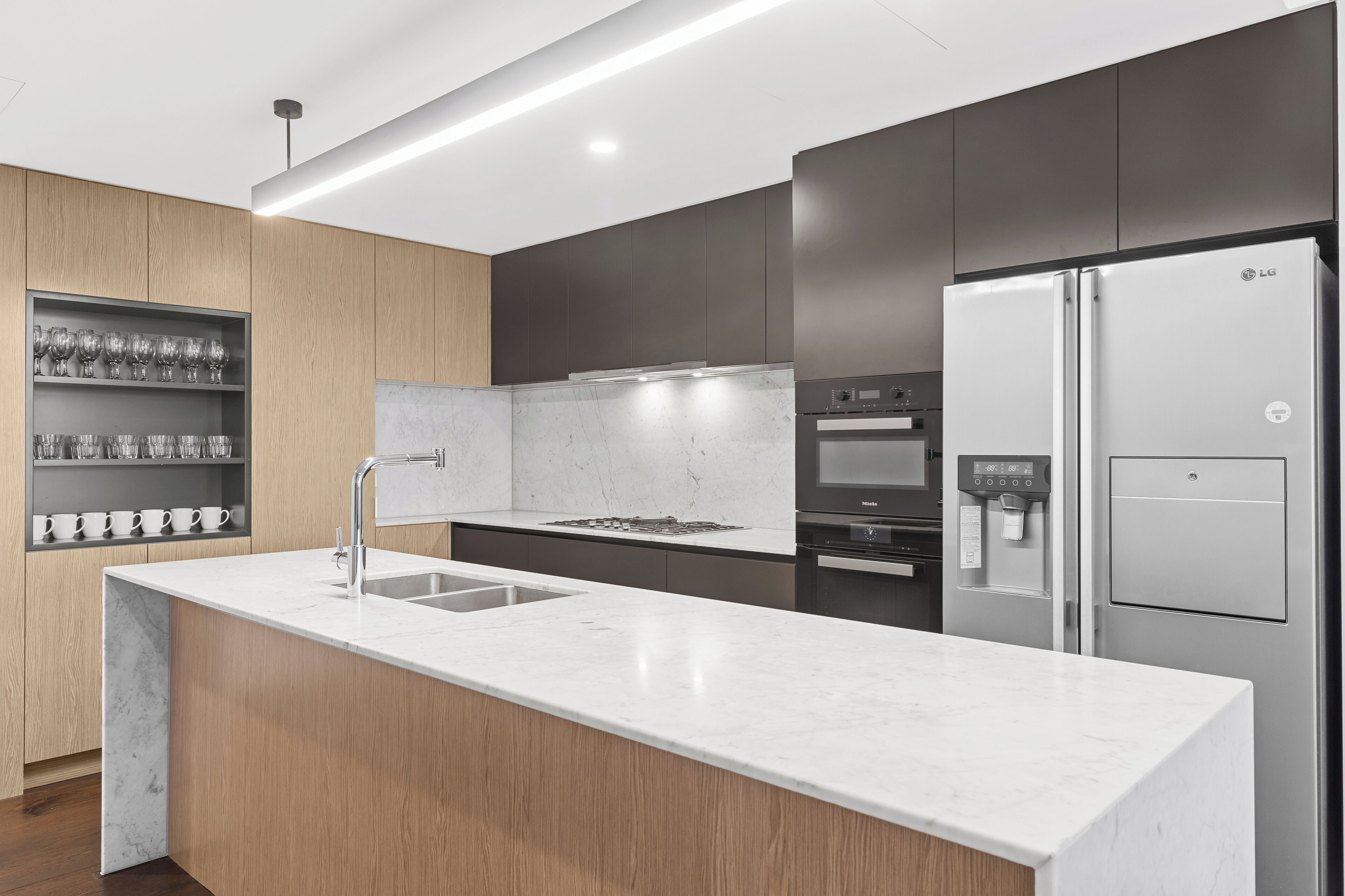 A modern kitchen with a marble countertop, stainless steel appliances, and wooden cabinetry.