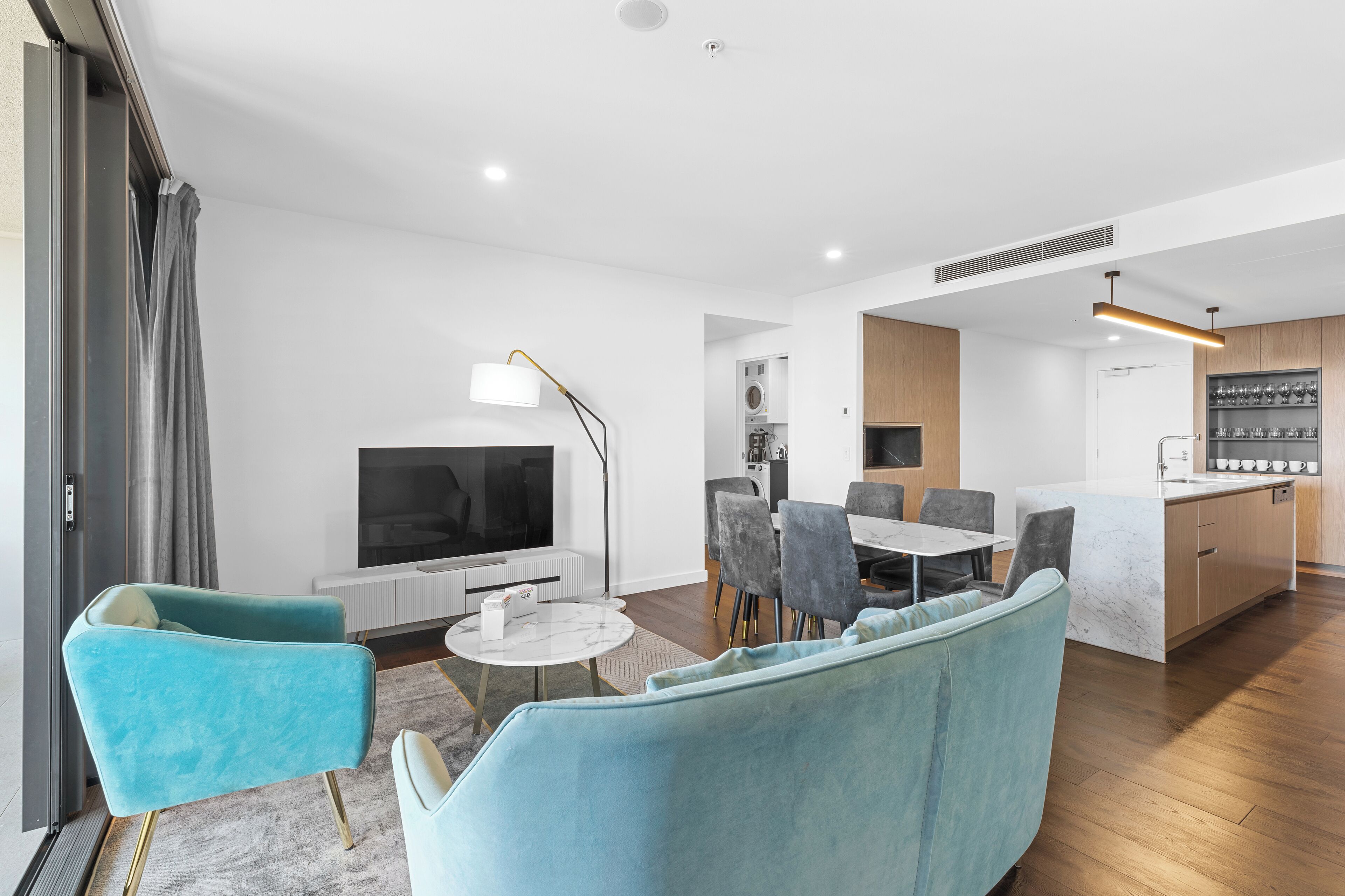 A modern apartment with a living room, dining area, and kitchen.
