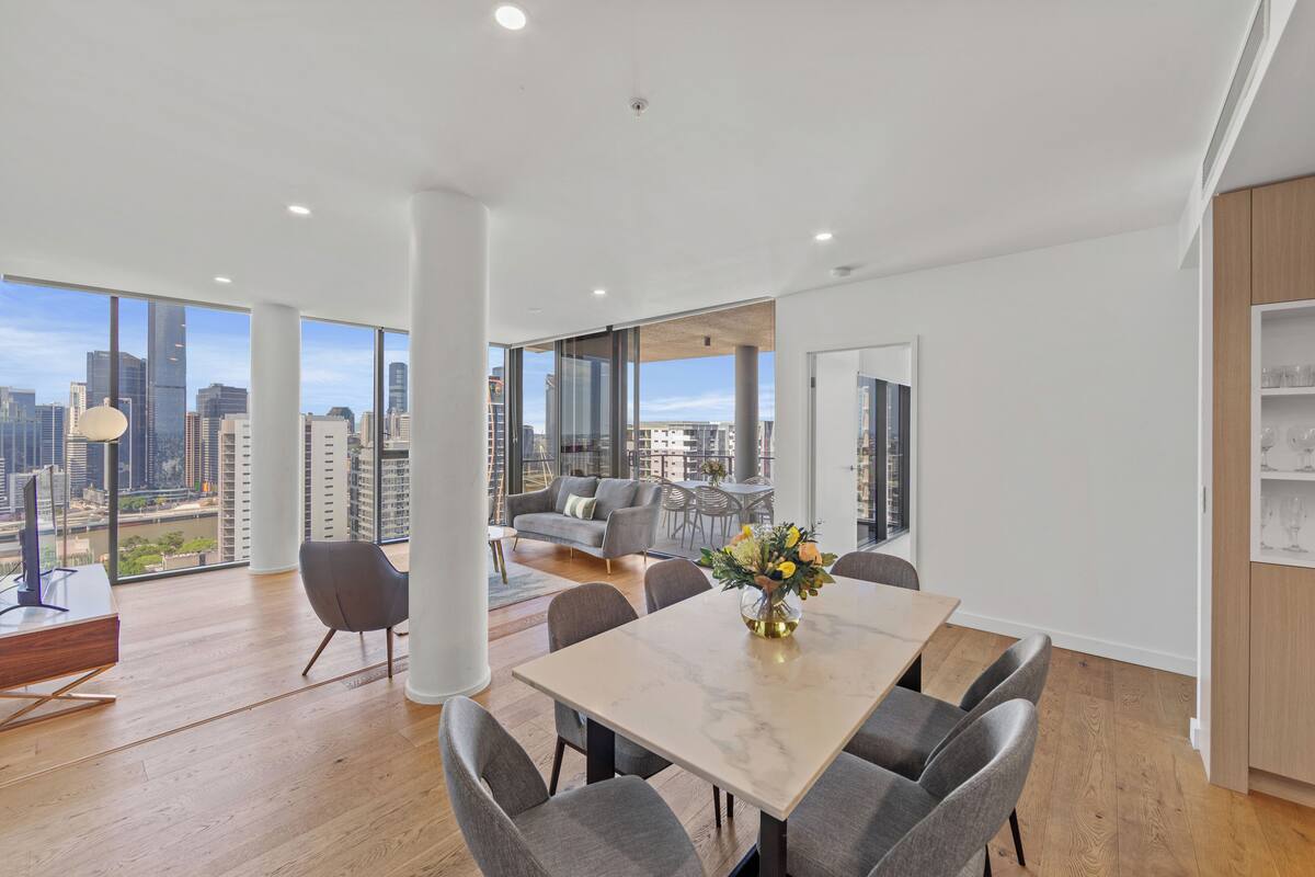 Una sala de estar moderna con un ventanal grande, un comedor con una mesa de mármol y vistas a la ciudad.