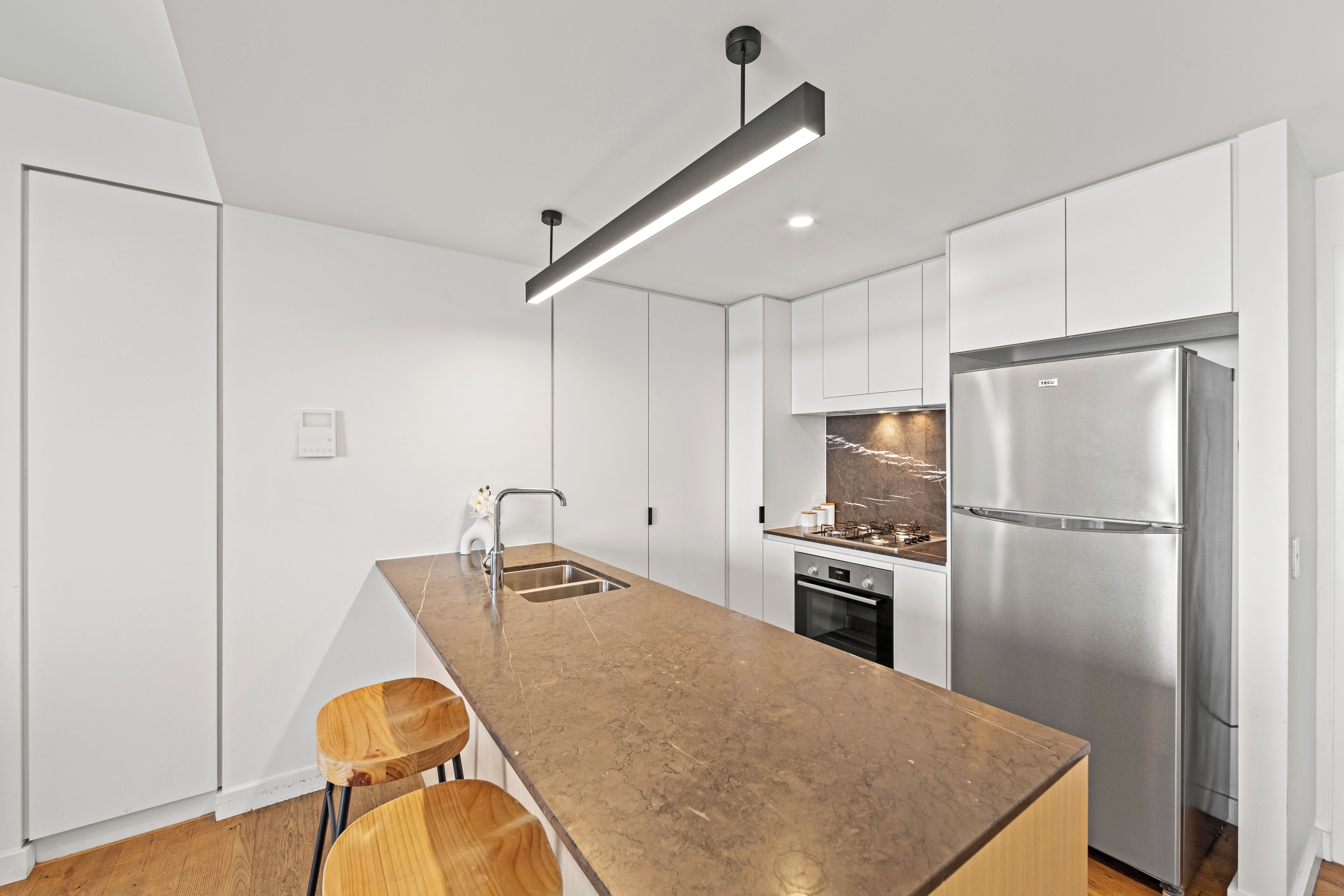 A modern kitchen with a long island, stainless steel appliances, and minimalist design.