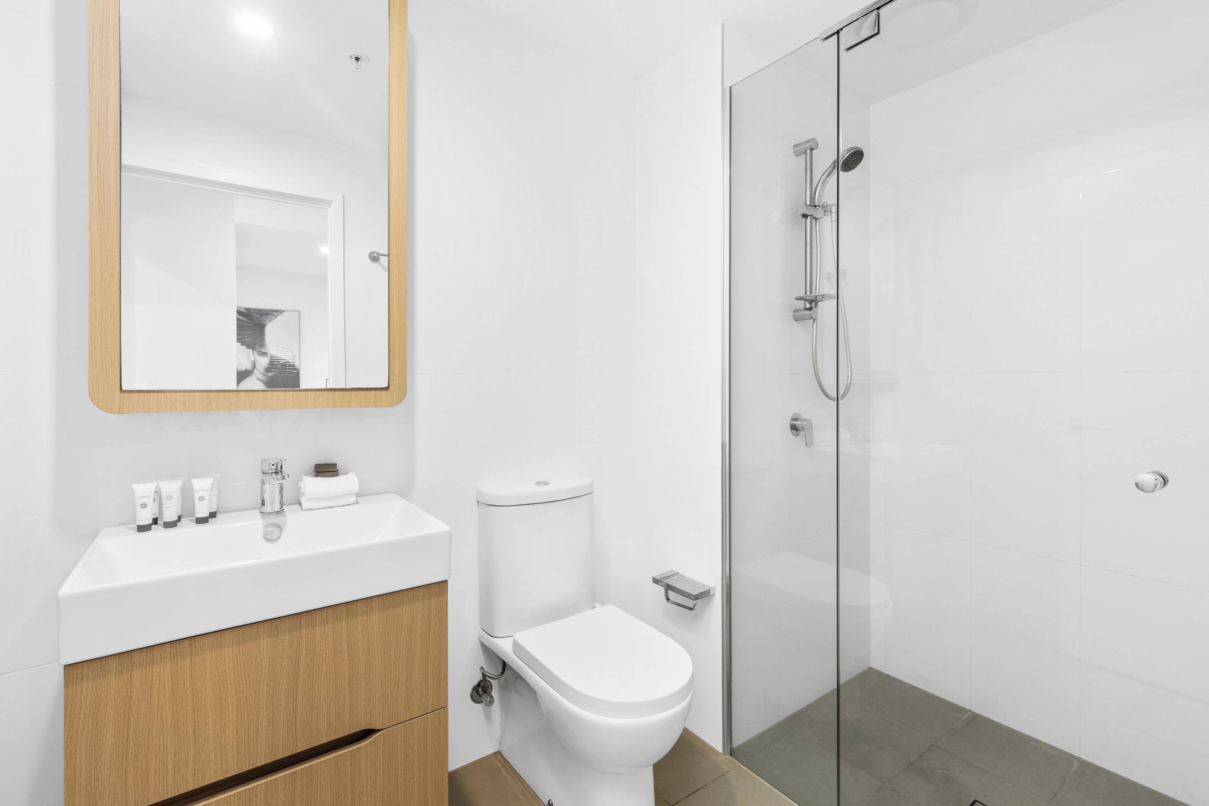 Un bagno moderno con lavandino bianco, servizi igienici e cabina doccia in vetro.