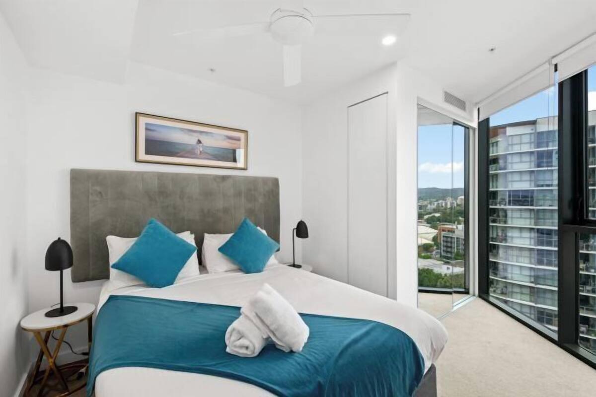 Una habitación de hotel moderna con una cama grande, vistas de la ciudad y un balcón.