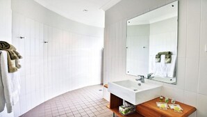 Un baño moderno con lavamanos blanco, espejo y paredes con azulejos.