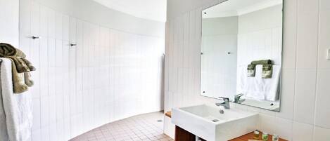 A modern bathroom with a white sink, mirror, and tiled walls.