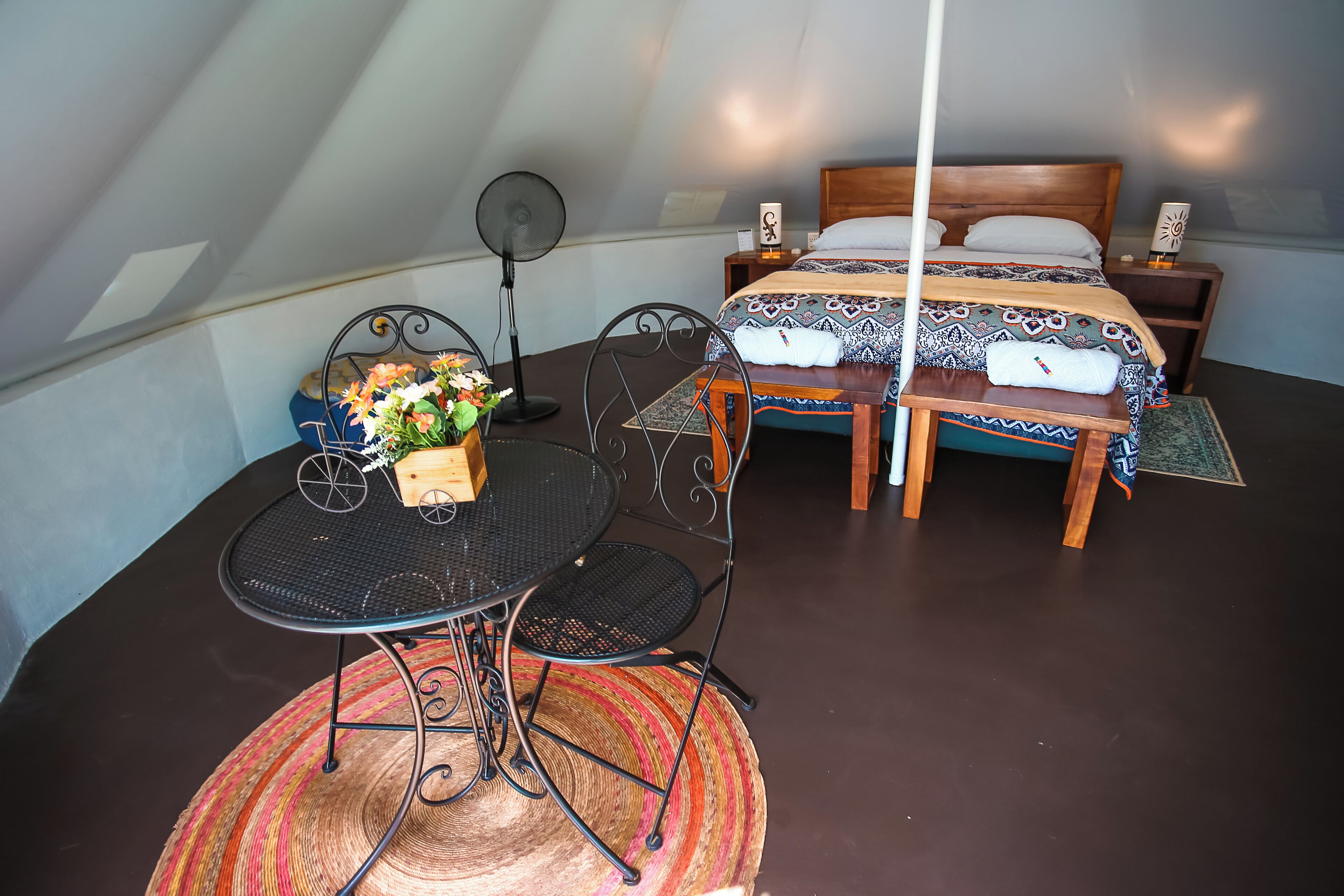 Una habitación acogedora con cama, mesita de noche y un pequeño comedor con mesa y sillas.