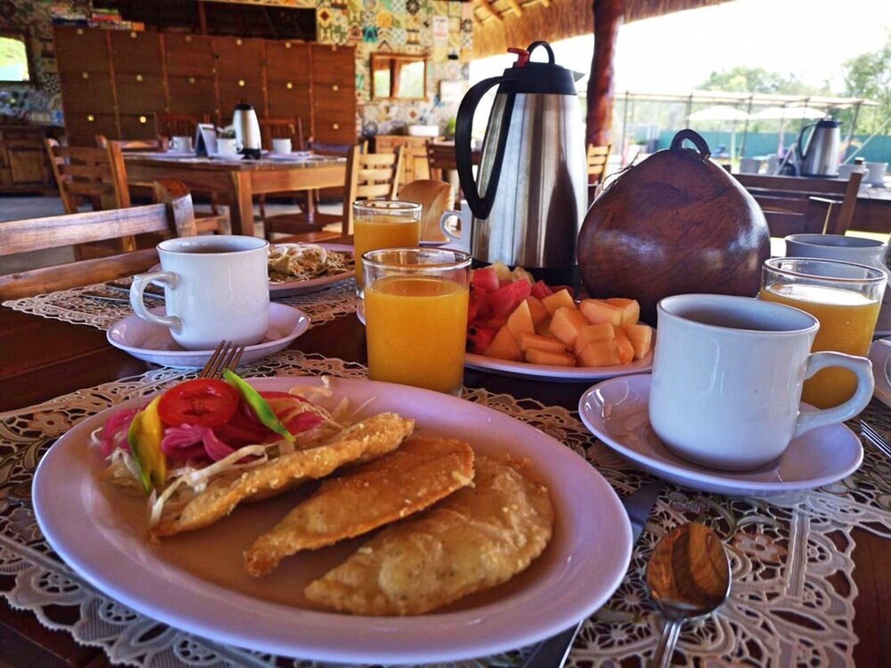 Una escena de desayuno con platos de comida, café y jugo.