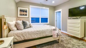 A bedroom with a bed, a ceiling fan, a TV, a dresser, and a window with blinds. - Boutique-Style Retreat in Reynolds Village (Asheville)