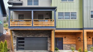 A multi-story residential building with a two-story balcony, a garage, and a wooden deck. - Boutique-Style Retreat in Reynolds Village (Asheville)