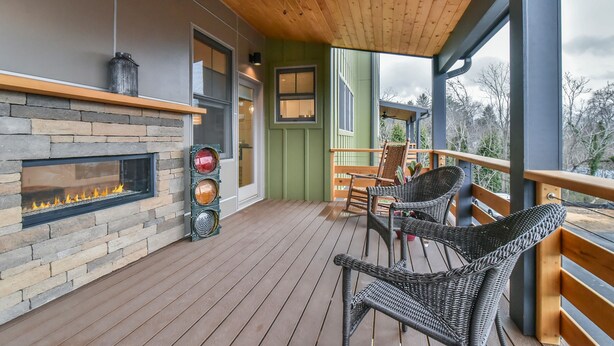 A wooden deck with wicker chairs, a fireplace, and a view of the outdoors. - Boutique-Style Retreat in Reynolds Village (Asheville)
